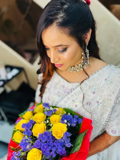 A soft, romantic party look. The client is holding a bouquet of flowers, and her makeup is kept fresh and dewy to match the delicate vibe.