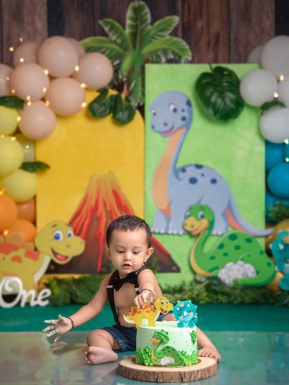 This little one is carefully inspecting the dinosaur on his cake before the big smash. A moment of cute contemplation.