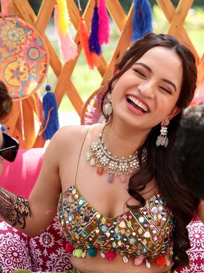 A happy and laughing bride, enjoying her mehendi ceremony in our colourful jewellery.