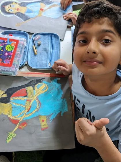 A young artist with his vibrant oil pastel drawing of a deity. He has used bold colors to make his artwork stand out.