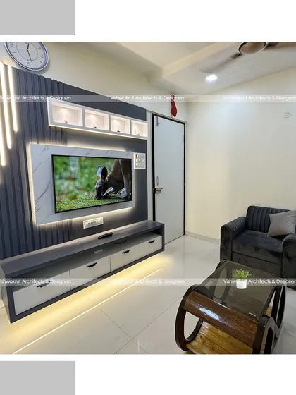 The living room in a 1BHK apartment, showing the modern TV unit with vertical light strips and a compact sofa. This design is perfect for smaller living areas, providing storage and style without overwhelming the space.