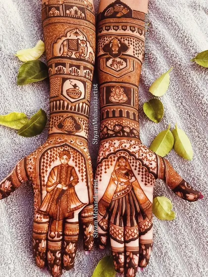A beautifully styled shot of a bride and groom portrait mehandi, surrounded by green leaves.
