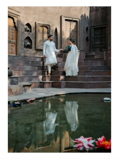 A classic pre-wedding pose of a couple descending the steps of a traditional stepwell. The reflection in the water adds a layer of depth and artistry to this heritage-themed portrait.