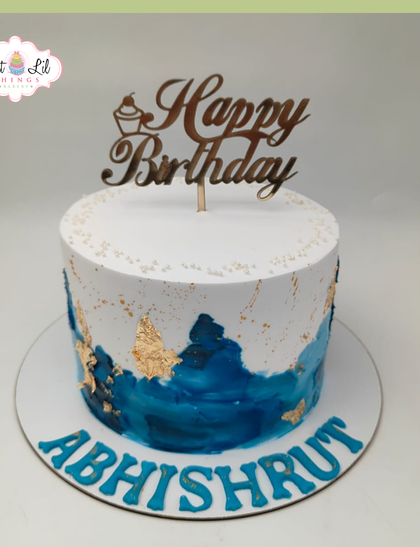 A sophisticated birthday cake for Abhishrut, featuring a deep blue watercolor design accented with shimmering gold leaf.
