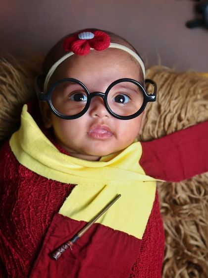 Another take on our Harry Potter theme, this time with a Gryffindor scarf and glasses. This little one looks ready to cast a spell with their wide-eyed expression.