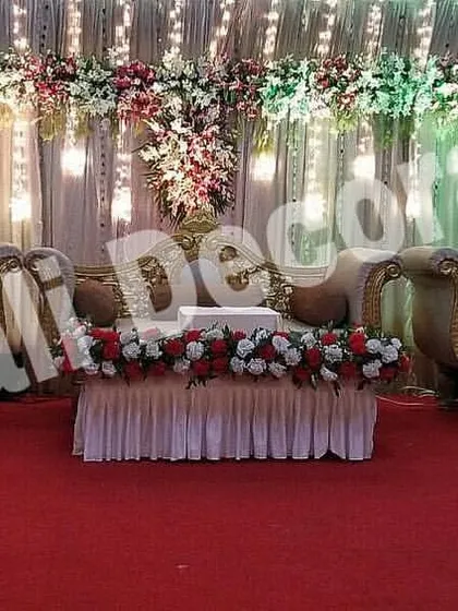 This is a classic reception stage setup with a red carpet, perfect for making a grand statement. The rental includes a full set of traditional golden furniture and a backdrop of drapes and floral arrangements.