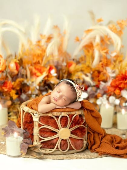 A wide shot of the autumn-themed setup, showing the beautiful arrangement of pumpkins and warm colors surrounding the sleeping newborn.