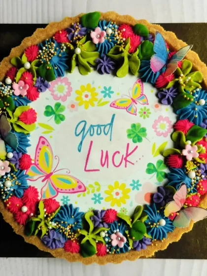 Wishing someone 'Good Luck' on a new adventure has never been sweeter. This chocolate tart is adorned with colorful butterflies and flowers, carrying a heartfelt message for someone moving abroad.