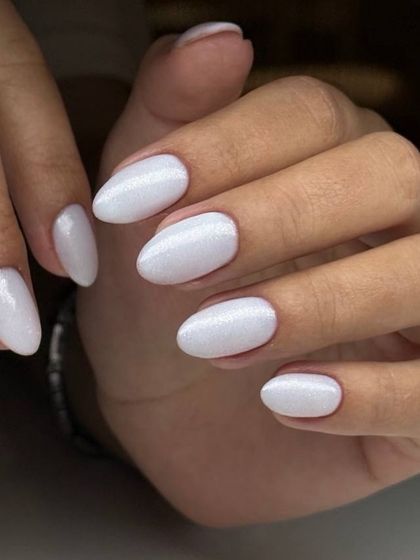 A pearly white manicure on oval-shaped nails. The subtle shimmer gives this classic white a beautiful, iridescent finish.