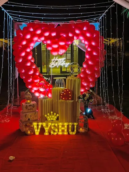 We specialize in creating unforgettable romantic surprises. This stunning outdoor cabana setup features a heart-shaped balloon arch, a red carpet entrance, and magical fairy lights, perfect for a birthday or anniversary celebration.