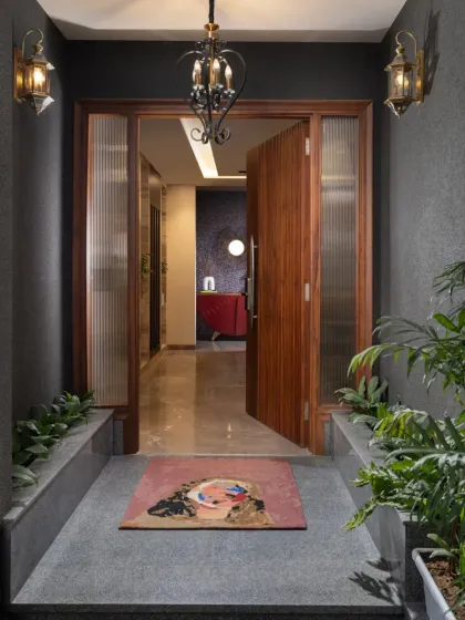 The journey into the home begins here. This entryway features a modern wooden door, classic lanterns, and a glimpse of the bold, artistic interior that awaits.