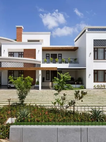 A daytime view of a modern villa, showcasing how the structure interacts with the surrounding landscape. The clean white walls are accented with wood and stone, creating a connection to nature.