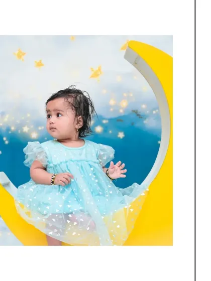 A beautiful profile shot of a baby girl on the moon prop, looking off to the side. The starry background and her delicate dress create a truly enchanting and peaceful portrait.