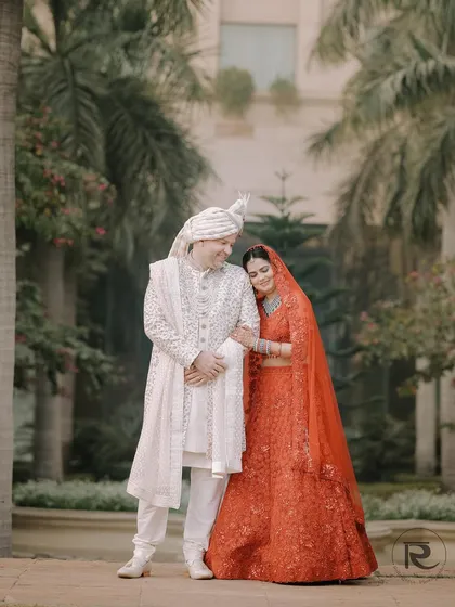 A quiet moment of connection on the wedding day. The bride, in a stunning red lehenga, rests her head on her groom's shoulder, a perfect blend of traditional attire and modern love.