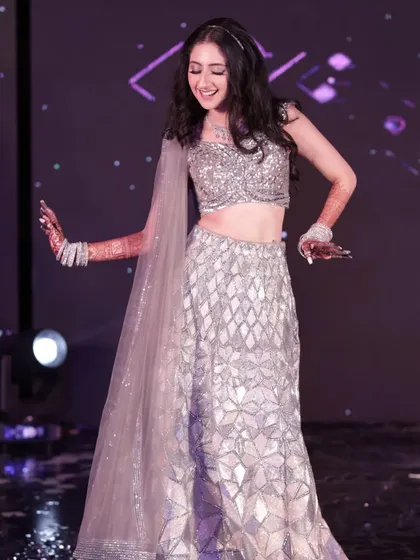 A full length view of the bride's sangeet performance. Her shimmering lehenga and radiant makeup catch the stage lights beautifully, making her the star of the show.