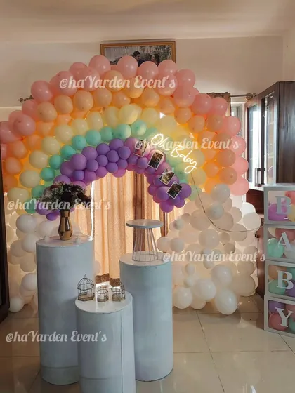 Another view of the pastel rainbow baby shower, showing the 'BABY' blocks and pedestals for the cake and gifts.