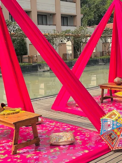 A poolside seating arrangement for the Haldi, with bright pink drapes and a colorful umbrella, creating a fun and relaxed vibe.