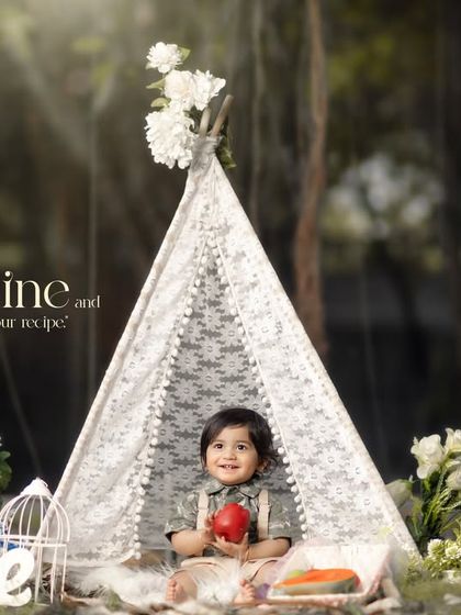 Sunshine and laughter, that's our recipe. A happy baby boy enjoys a snack in our outdoor teepee setup during his first birthday session.