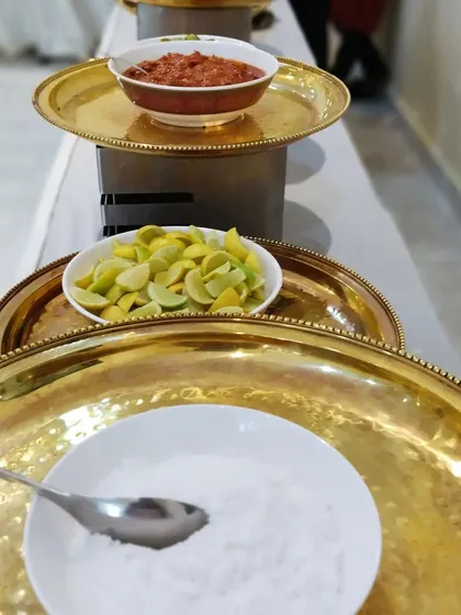 Even the smallest details matter. We provide a selection of fresh condiments like sliced lemons, salt, and homemade pickles, all presented neatly in traditional brass serveware.