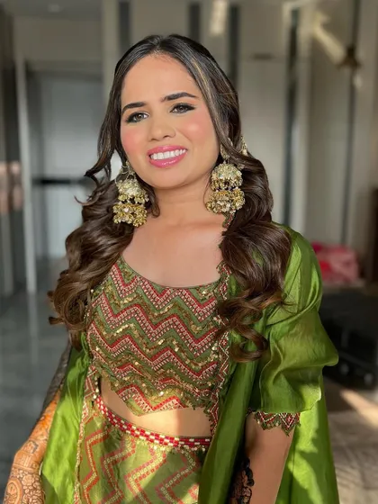 A beautiful Mehendi look featuring a stunning green outfit by Punit Balana. The makeup is kept fresh and glowing with a pink lip to complement the vibrant colours.
