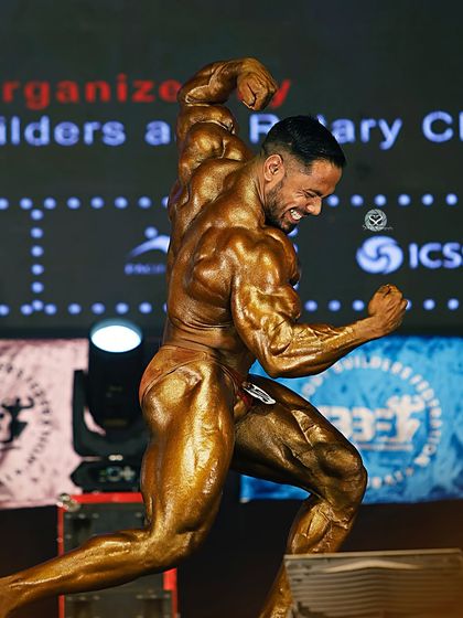 Executing a classic physique pose on the Mr. India stage. This pose highlights the lines, symmetry, and aesthetic flow of the body.
