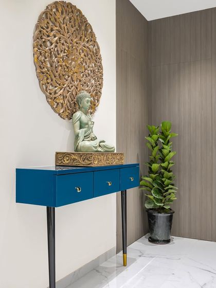 The entrance sets a tone of peace and harmony. A magnificent Buddha statue greets you, complemented by a sleek blue console table and a carved wooden art piece, creating a tranquil first impression.