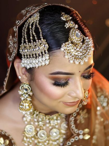 A side profile of a bride in a brown and gold lehenga, showcasing the intricate hairstyle and passamer jewelry.