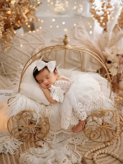 Our newborn sessions are designed to be a work of fine art. Here, a 15-day-old princess sleeps peacefully in a boho-themed carriage prop, surrounded by soft textures and warm light, showcasing our attention to detail in creating a dreamy, serene atmosphere.