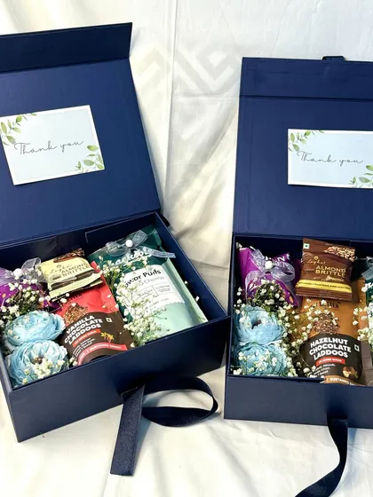 An example of our elegant corporate gift boxes. This deep blue box includes a "Thank You" note and is filled with a curated selection of gourmet snacks and treats.