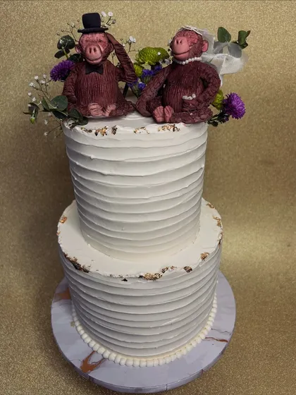 Our clients have the best ideas! This two-tiered wedding cake with a textured buttercream finish is topped with the most charming, custom-made monkey bride and groom toppers. It's proof that wedding cakes can be both elegant and playful.