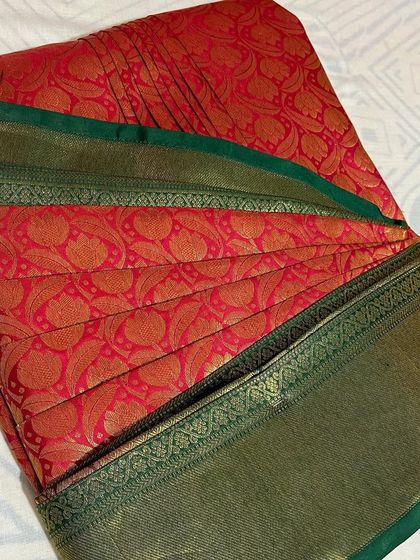 A red saree with a unique green border, pleated and ready. I can work with any saree from your collection.