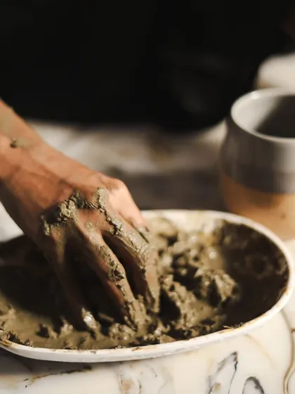 A detailed close-up of hands mixing the clay, emphasizing the natural, hands-on aspect of the skincare ritual.