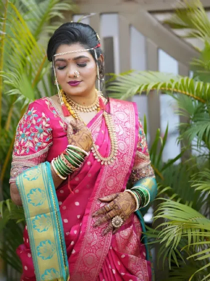 The bride looking elegant in her pink Paithani saree, complete with green glass bangles and a traditional nath.