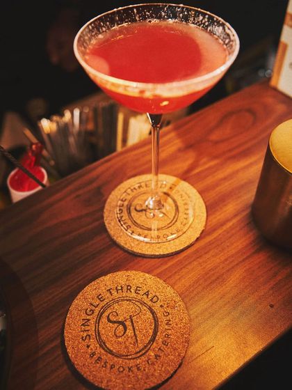A close-up of a vibrant red cocktail on the bar, ready to be enjoyed.