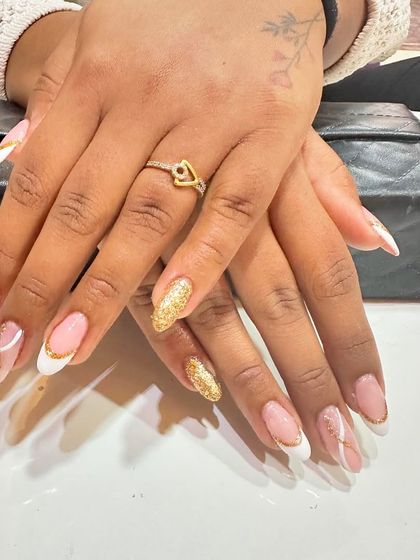 A fun and stylish take on the French manicure. This set features classic white tips, a full gold glitter accent nail, and delicate white swirls on a natural base.