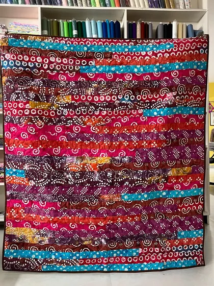 A vibrant Jelly Roll quilt made with colorful batik fabrics.