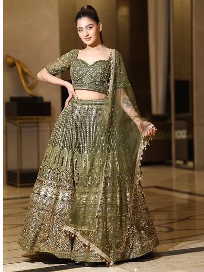 A full-length portrait of the olive green lehenga, showing its beautiful drape and the way it combines traditional embroidery with a modern silhouette.