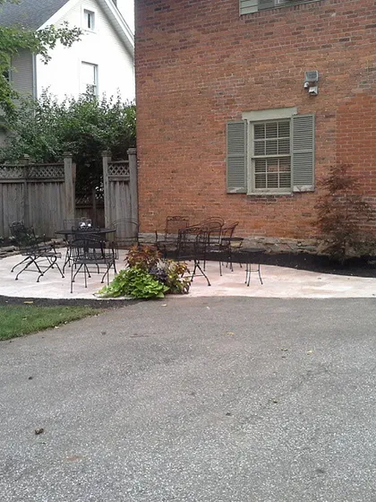 A wider view shows how the new paver patio fits in with the existing driveway and lawn, creating a much more defined and usable space.