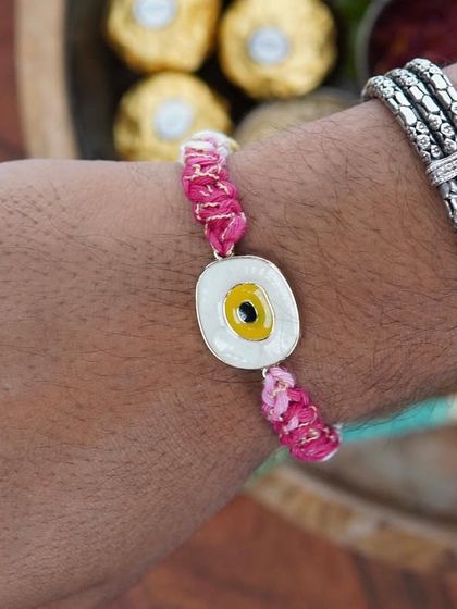A man's wrist adorned with the yellow Evil Eye Rakhi. It's a stylish and modern take on the traditional thread.
