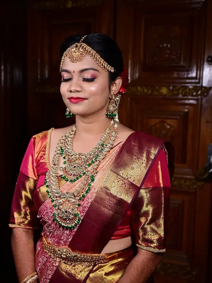 A close up on the bride's makeup, featuring shimmery pink and gold eyeshadow and a bold red lip.