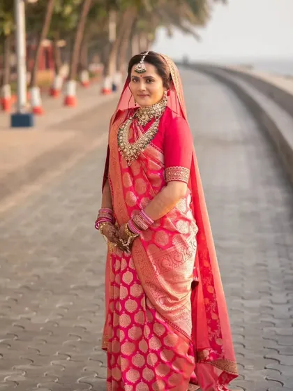 This bride's look was all about royal elegance. The makeup features a classic winged liner and a bold lip, paired with a traditional red saree and heavy jewelry for a truly regal appearance.