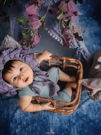 Celebrating the half-birthday milestone at six months old. This happy baby sits in a wicker basket with a '1/2' sign, showing off a huge, infectious giggle.