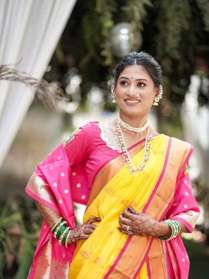 A stunning portrait of the bride in her vibrant yellow and pink saree, looking elegant and happy.