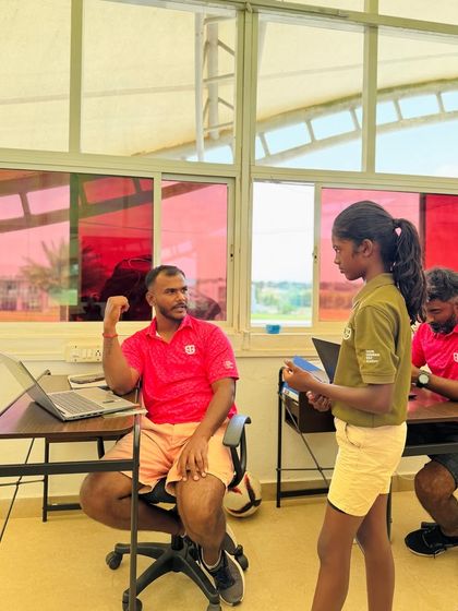 Coach Kiran reviewing a student's work. He sets high standards and gives each student his full attention, whether they are a young junior or an adult beginner.