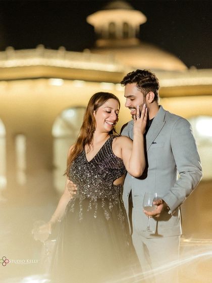 An elegant evening shot from a resort pre-wedding shoot. The couple shares a glass of wine by the pool, capturing a moment of quiet celebration and intimacy.