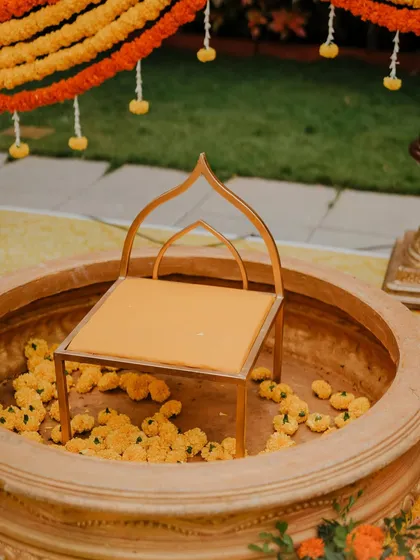 A detailed look at the Haldi seating, a modern-style chair placed within a traditional urli filled with marigold flowers. This blend of contemporary and classic design is a signature of our style.