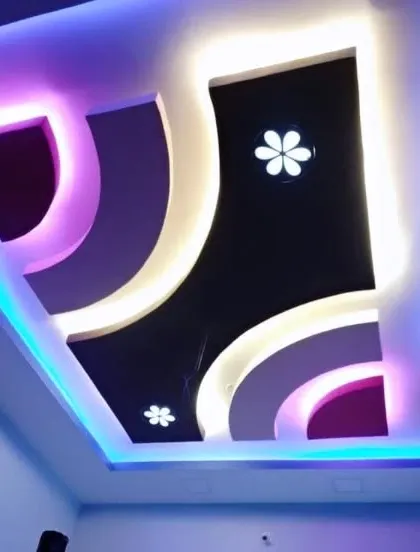 This ceiling combines curved shapes, multiple colors, and small, star-like lights. It's a creative design that brings a lot of personality to the room.