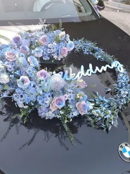 Your wedding ride deserves to be just as special as the occasion. We decorated this BMW with a unique crescent of cool-toned blue and lavender flowers, creating a sophisticated and stylish statement for the couple's journey.
