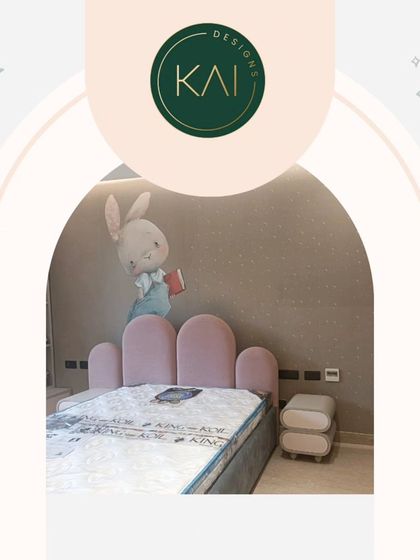 A charming bedroom designed for a child, featuring a bed with a soft pink, rounded headboard. The whimsical bunny wall art adds to the room's playful and gentle character.