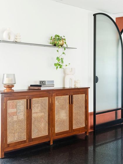 A dining room credenza with caned door fronts. This piece provides ample storage for dinnerware while adding a light, airy texture to the space, complementing the nearby arched doorway.